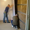 two men installing soundproofing onto a party wall