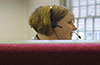 lady's head wearing headset showing above red desk screen